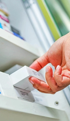 pharmacist pulling prescription off shelf